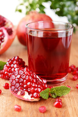 Ripe pomegranates with juice on table close-up
