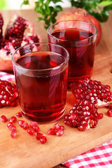 Ripe pomegranates with juice on table close-up