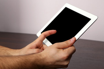 Hands using tablet PC on wooden table and light background