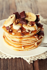 Stack of delicious pancakes with chocolate, honey, nuts and