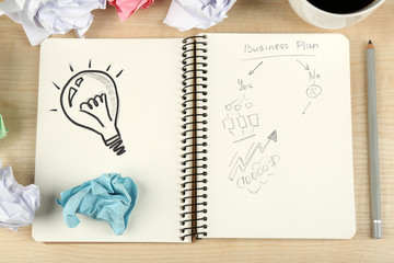 Symbol of idea as light bulb in notebook with crumpled paper