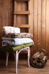 Warm plaids on chair on rustic wooden background