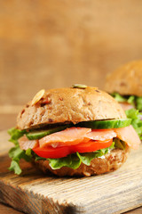 Sandwiches with salmon on cutting board, on wooden background