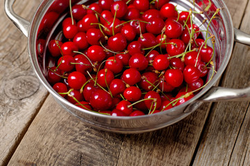 Sweet cherries in colander on color wooden background