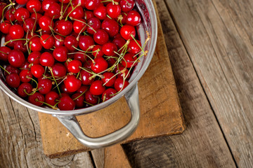 Sweet cherries in colander on color wooden background