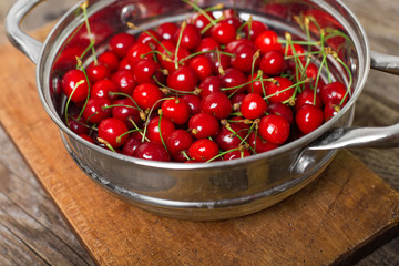 Sweet cherries in colander on color wooden background