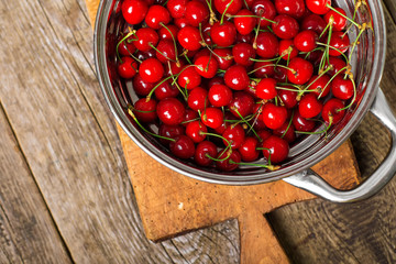 Sweet cherries in colander on color wooden background