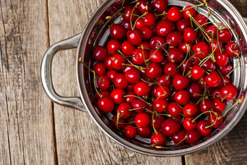 Sweet cherries in colander on color wooden background
