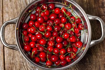 Sweet cherries in colander on color wooden background