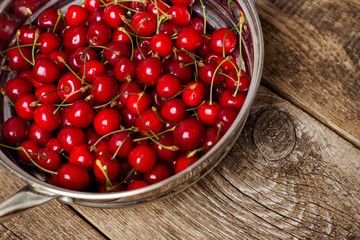 Sweet cherries in colander on color wooden background