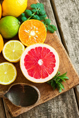 Obraz na płótnie Canvas Halves of fresh citrus fruits on wooden background. Orange, grap