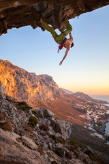 Male climber on overhanging cliff before sunset