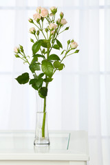 Beautiful bouquet of flowers in vase on window background