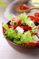 Greek salad in bow on wooden table background
