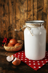 Milk can with eggs and eggshell on rustic wooden background