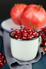 Juicy ripe pomegranate on wooden table, on dark background