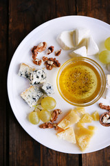 Different sort of cheese with grape, nuts and saucer