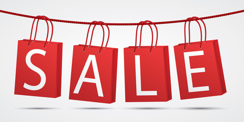 Realistic red shopping bags hanging on rope with text sale