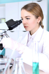 Young female scientist with microscope in laboratory