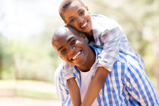 african woman enjoying piggyback ride on boyfriend