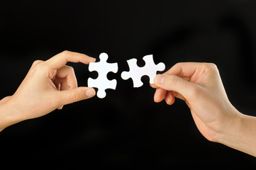 黒い背景で白いパズルのピースを持っている人間の手 Wall Mural Beeboys