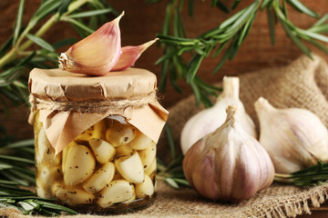 Canned garlic in glass jar on wooden background