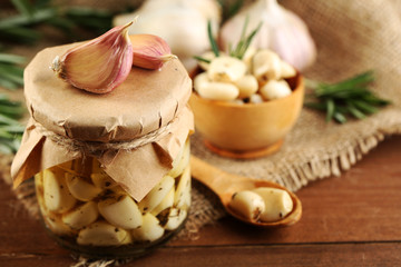 Canned garlic in glass jar on wooden background
