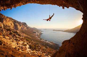 Rock climber hanging on rope while climbing cliff