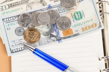 US coins and banknotes with pen on a notebook
