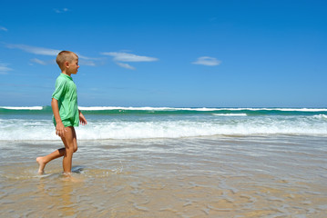 Young boy walking along the waters edge