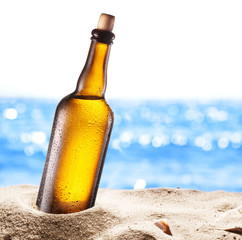 Photo of cold beer botle in the sand.