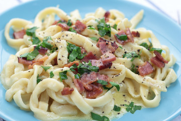 Fresh and beautiful fettuccine carbonara on blue plate.