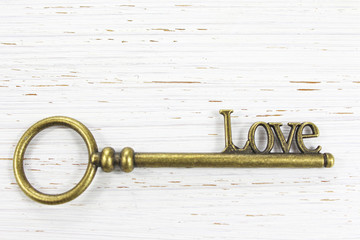 The key to Love Brass key on white wooden background