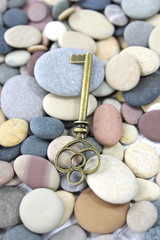 Fototapeta na wymiar Antique Brass key on a pebble beach
