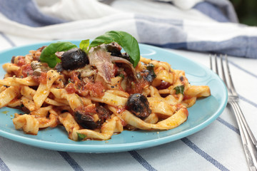 Blue plate of freshly cooked fettuccine puttanesca.