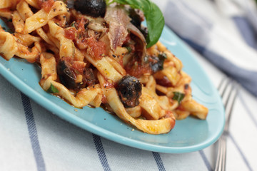 Blue plate of freshly cooked fettuccine puttanesca.