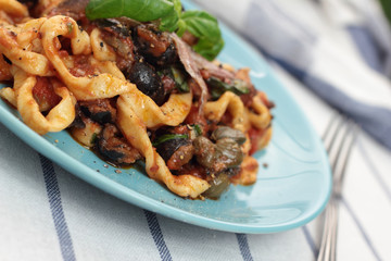 Blue plate of freshly cooked fettuccine puttanesca.