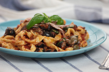 Blue plate of freshly cooked fettuccine puttanesca.