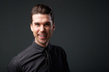 Fototapeta premium Attractive young man smiling in black shirt and tie