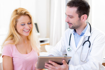 Young doctor showing results on tablet to patient