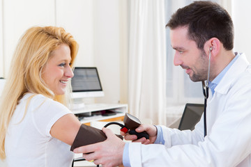 Young attractive doctor checking patient's blood pressure