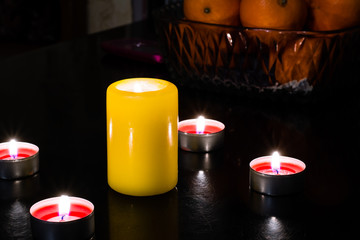 Still life of candles of different colors and fruits on the tabl