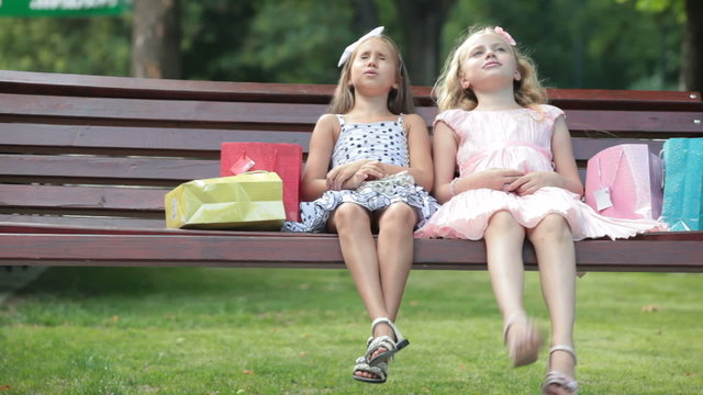 little girls with shopping bags relaxing on the bench