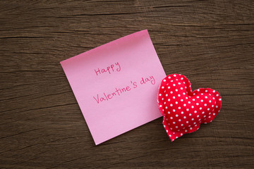 Red polka dot hearts with valentine note on wood texture