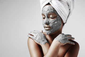 woman with a grey facial mask on her face and hands