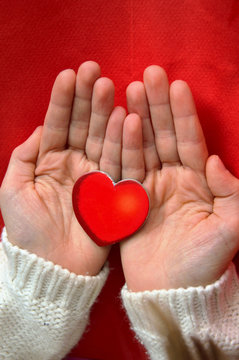 Red heart hold in the palms by a girl