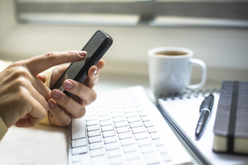 Businesswoman using mobile phone, cup of coffe, computer.