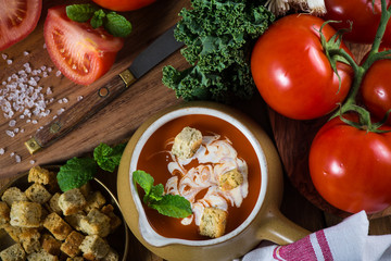 Fresh creamy tomato soup on rustic wooden table