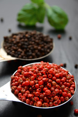 Pink and black peppercorns on a spoon