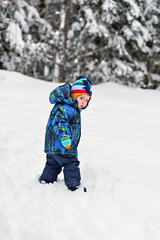 Fototapeta na wymiar Little Boy Looking Back in a Snowy Forest